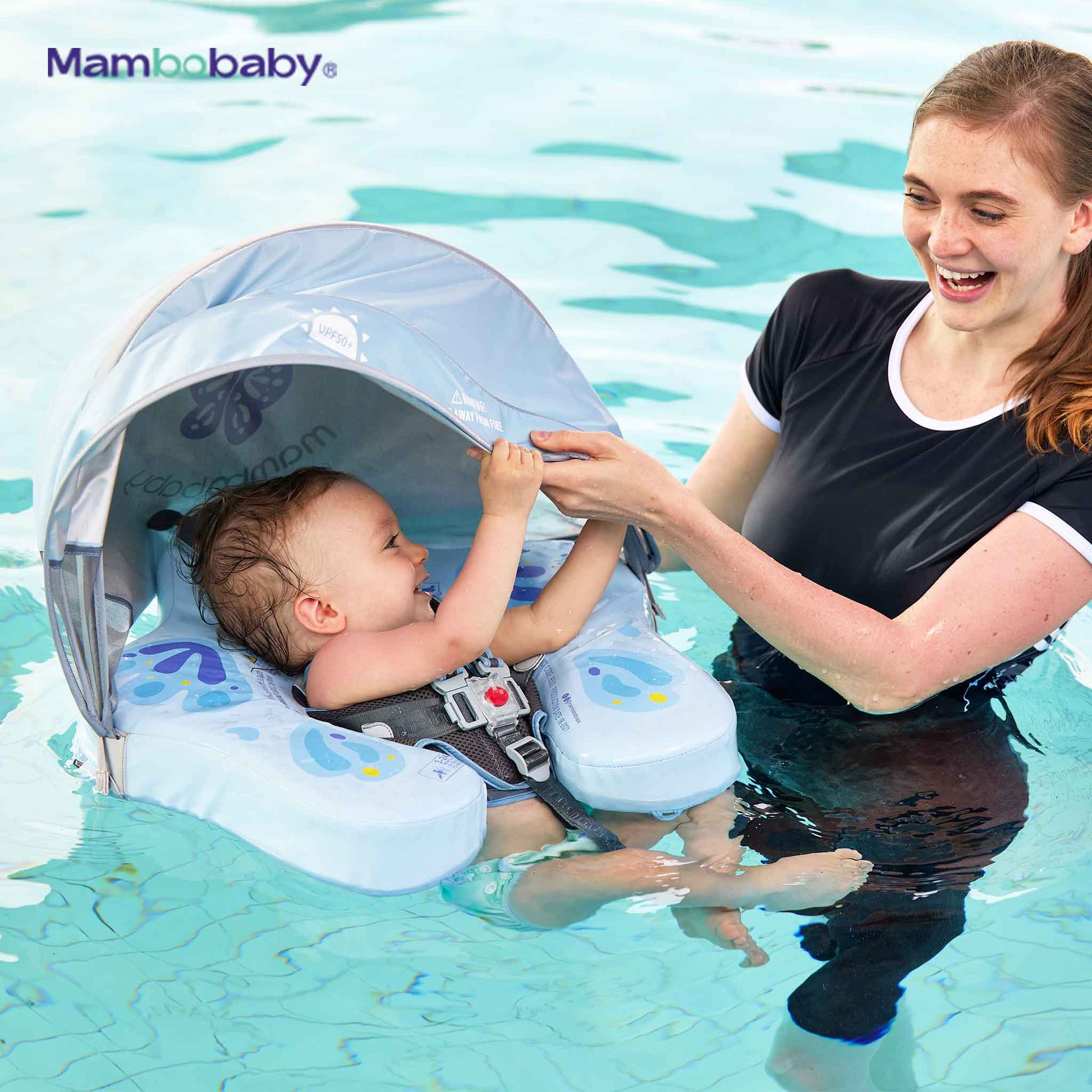 Toddler smiling and reaching for the canopy while floating in Mambobaby float