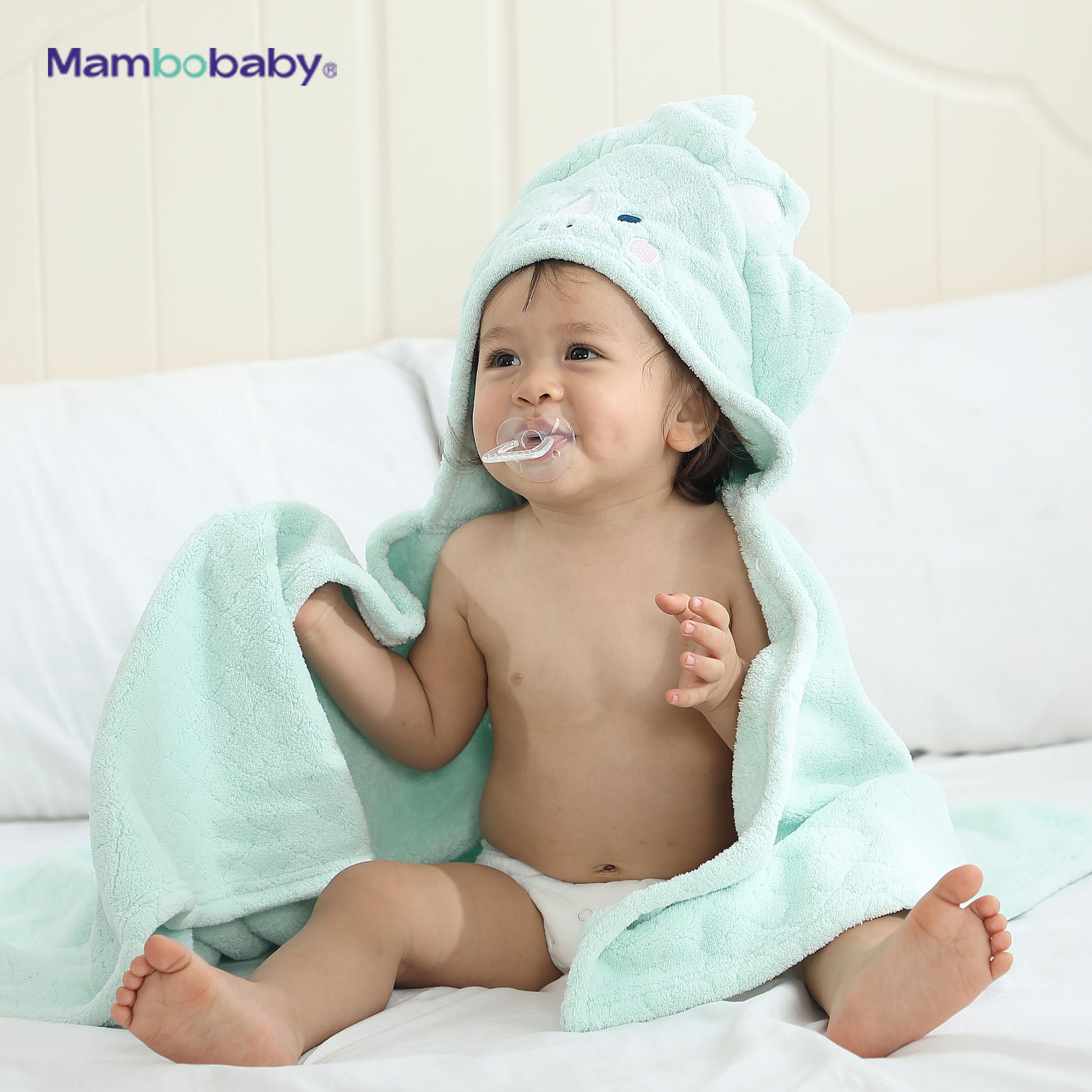 Baby sitting wrapped in Mambobaby hooded towel, hood up, Dino Mint