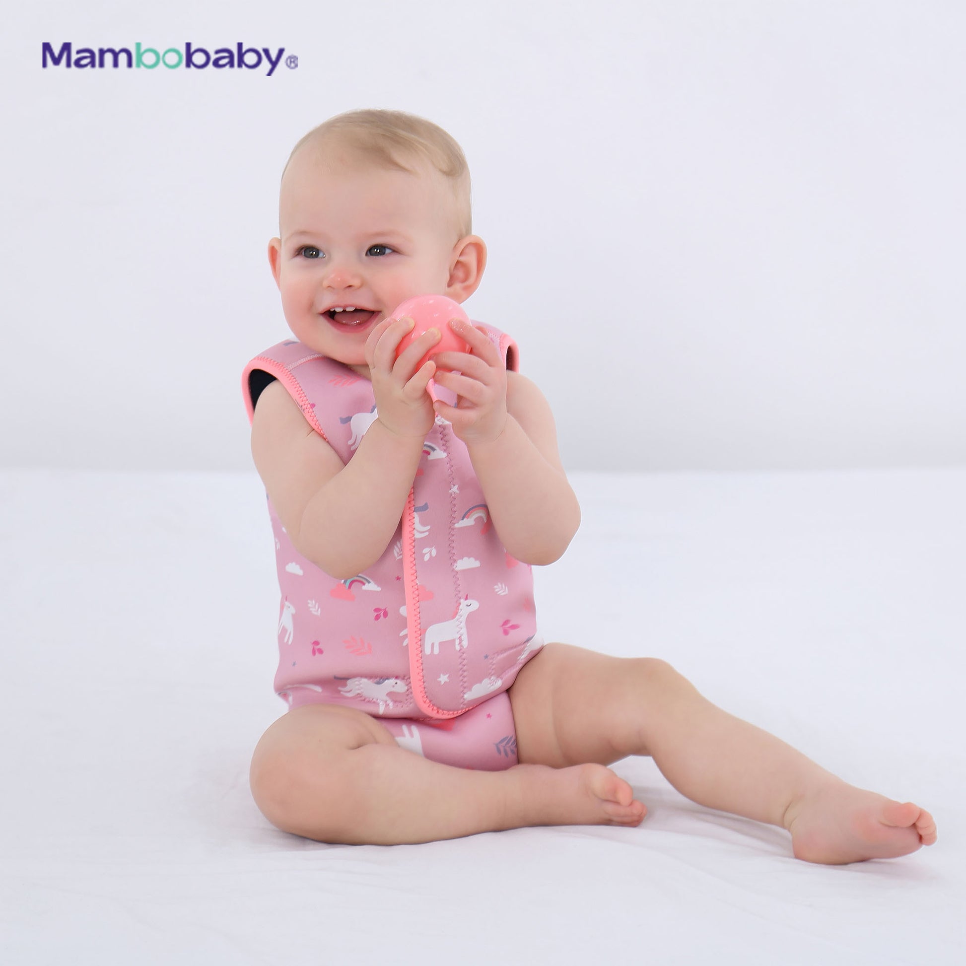 Baby sitting and playing while wearing Mambobaby thermal wetsuit in pink